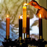 Advent Wreath with Candles Lit, With Hand of Person in Robe Lighting Center Candle