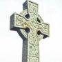 File Photo of Stone Celtic Cross Next to Stone Wall of Building