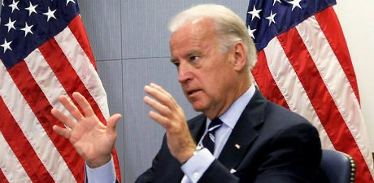 File Photo of Joe Biden, Mostly Turned to the Side, Gesturing with Both Hands, with U.S. Flags in the Background, adapted from image at ar.usembassy.gov