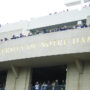 'Notre Dame' Stadium Facade with People Looking Over Edges, with 'University of Notre Dame' Engraved in Gold Lettering