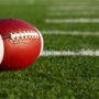 File Photo of Football on Turf Near Sideline in Bright Sunlight