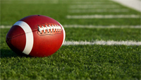 File Photo of Football on Turf Near Sideline in Bright Sunlight